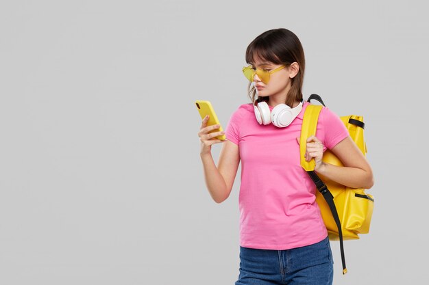 An Asian teenager woman in heart-shaped glasses holds a mobile phone in hands. New Gadget Advertising