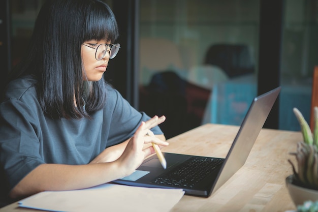 Adolescente asiatico che lavora al computer labtop nel soggiorno di casa