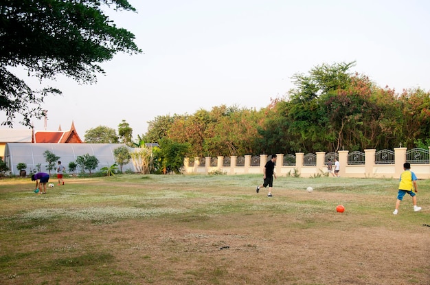 Asian thai father training and playing football or soccer with son at playground on yard in public garden park on February 17 2017 in Nonthaburi Thailand