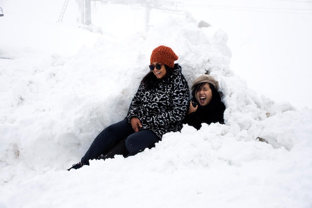 オーストリアのチロルで雪が降っている間、アジアのタイ人の娘と母が旅行し、カウネルグラット自然公園の山の頂上で雪と一緒に写真を撮るためにポーズをとる