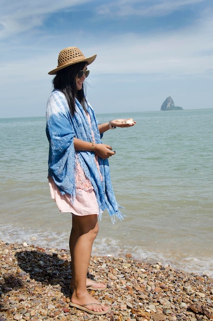 パンガータイのヤオノイ島の石のビーチで手に岩と貝殻を保持してポーズをとるアジアのタイの女性