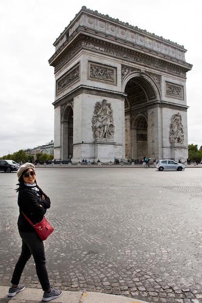 Asian thai woman travlers posing with Arc de triomphe de l'Etoile or Triumphal Arch of the Star at Place Charles de Gaulle on September 6 2017 in Paris France