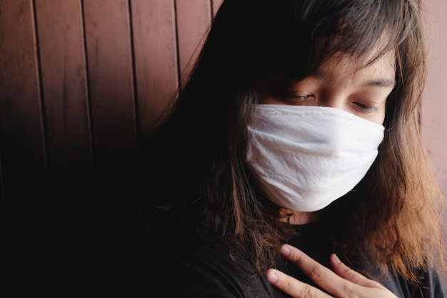 태국의 Covid-19 또는 Corona 바이러스 및 대기 오염 값 Pm 2.5를 방지하기 위해 흰색 천 마스크를 착용 한 아시아 태국 여성. 그녀는 호흡기 시스템에서 질식하고 있습니다. 건강과 질병 개념