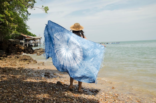 Asian thai women relax and playing indigo tie dye fabric shawl on the stone beach at andaman sea and ocean at Ko Yao Noi in Phang Nga Thailand