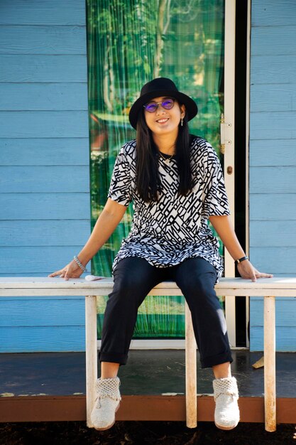 Asian thai women travelers sit posing portrait on patio of\
retro vintage wooden hut of resort and homestay in morning time in\
pak chong city at nakhon ratchasima thailand