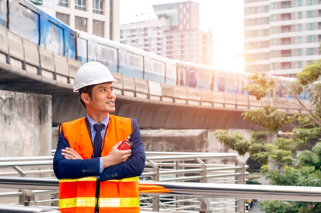 Asian thoughtful engineer smiling with arms crossed.