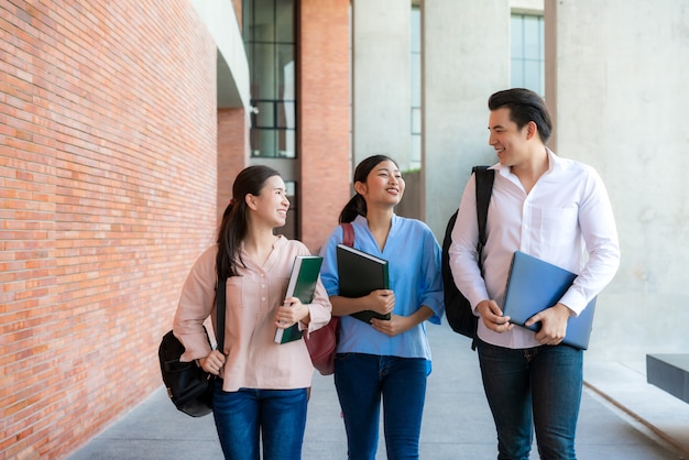 アジアの3人の学生が大学で歩いて話している