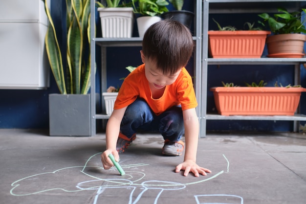 Asian toddler boy child drawing with colored chalk at home garage