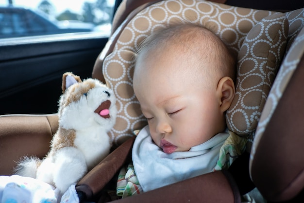 Asian toddler boy child sleeping in car seat. Child traveling safety on the road. Safe way to travel fastened seat belts in vehicle with young kid concept
