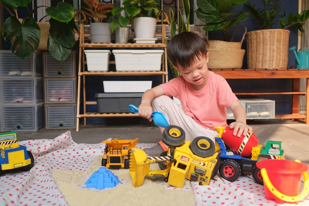 Ragazzo asiatico del bambino che gioca con la sabbia cinetica a casa, bambino che gioca con macchinari per costruzioni giocattolo, educazione montessori, gioco creativo per bambini concetto