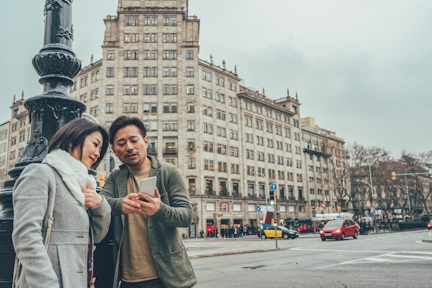 Азиатская туристическая пара смотрит на мобильный телефон