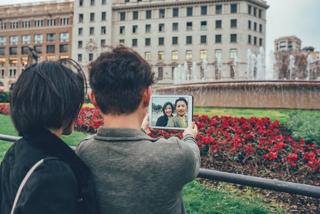 Asian tourist couple taking a selfie on the tablet