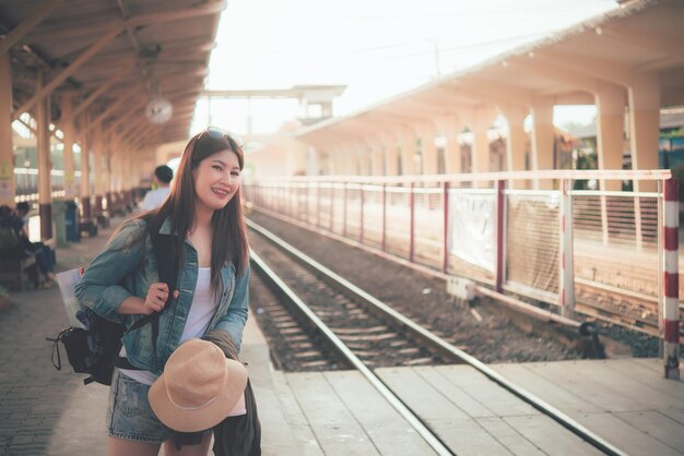 아시아 관광객은 기차역에서 기차를 기다립니다태국 힙스터 여성은 여행을 갑니다카메라를 손에 들고