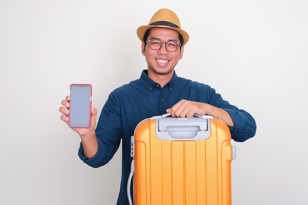 Asian tourist with luggage smiling happy while showing blank phone sccreen