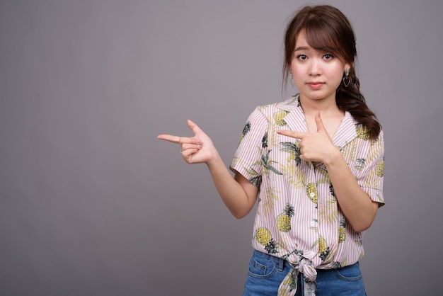 Asian tourist woman pointing finger and showing copyspace