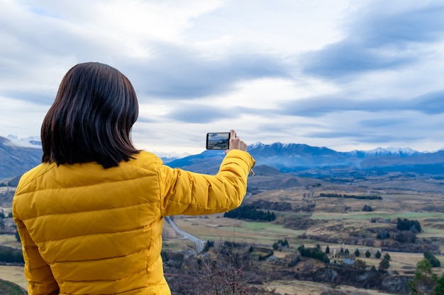 写真 クイーンズタウン南島ニュージーランドで携帯電話で写真を撮るアジアの観光女性