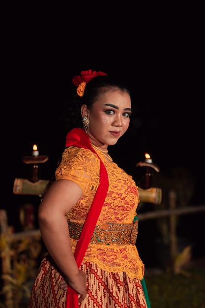 An Asian Traditional dancer in an orange dress with a red scarf and makeup performing at the dance festival