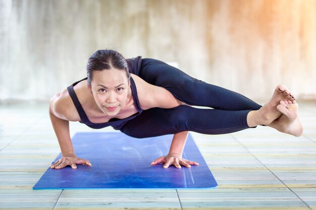 Asian trainee strong woman practicing difficult yoga pose 