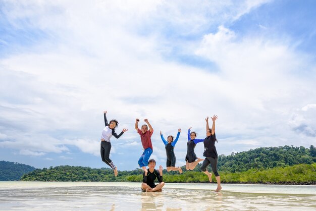 Photo asian traveler group are family happy life enjoy jumping together at the beach in summer thailand