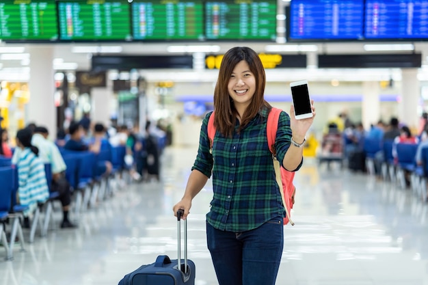 Asian traveler with luggage showing the smart mobile phone for check-in