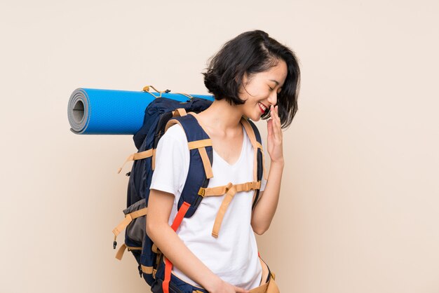 Donna asiatica del viaggiatore sopra la parete isolata che sorride molto