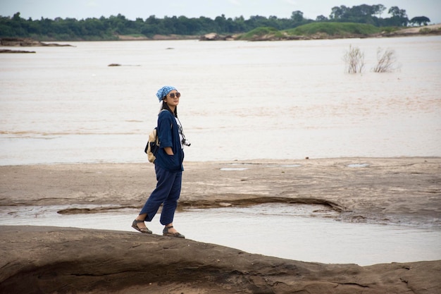 Asian travelers thai woman travel walking and posing take photo at Sam Pan Bok is known as the Grand Canyon of Thai in Mekong river whiling rainy season at Ubon Ratchathani Thailand