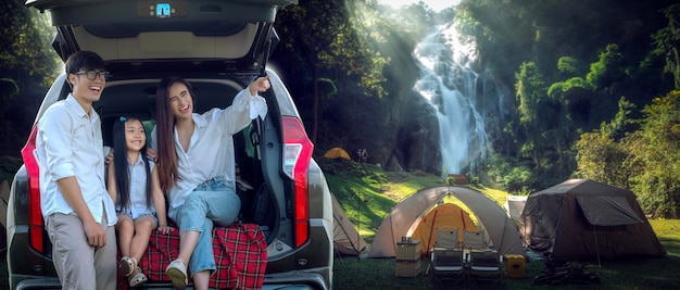 アジアの旅行者の家族はタイのチェンマイでテントで寝るためにSUV車でキャンプに行く