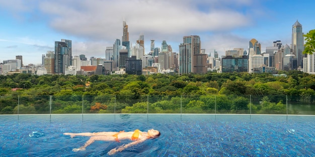 Photo asian traveller woman sleep and relax at swimming pool on hotel roof top with bangkok city view thai