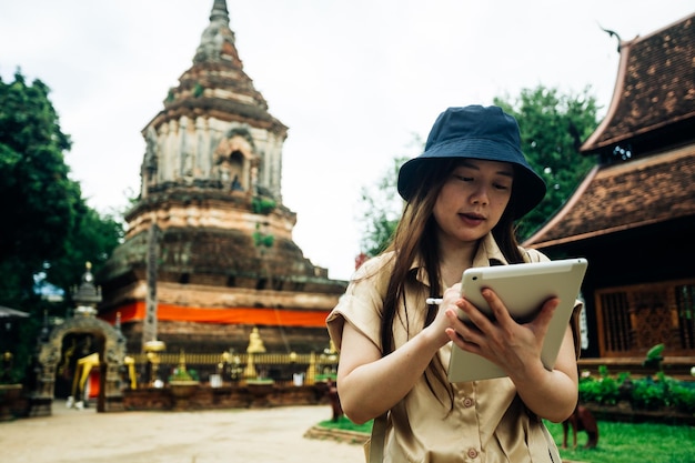 태국 치앙마이 지방의 오크몰리 사원에서 태블릿을 들고 있는 아시아 여행자 여성
