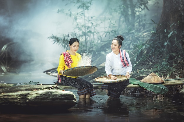 Asian Two beautiful women in traditional dress sitting segregation rice.