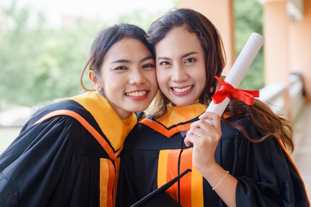 The Asian university graduates in graduation gown and a mortarboard cap with a degree certificate in hand celebrating education achievement in the commencement ceremony. Congratulations to graduations