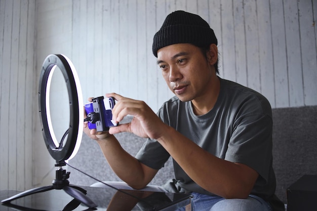 Asian vlogger man preparing equipment for live broadcasting, setting mobile phone before recording.