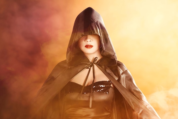 Asian witch woman with a cloak standing with dramatic background