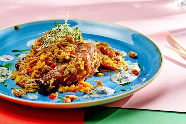 Азиатский рис вок с курицей, арахисом и овощами в тарелке на ярком фоне. Выборочный фокус, жесткий свет