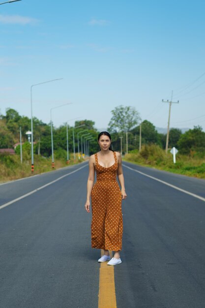 Asian Woman 40s LGBT transgender express feeling Happy Smile fun under sunshine on empty street road and flower field over blue sky mountain Female poses for fashion shooting in outdoors landscape