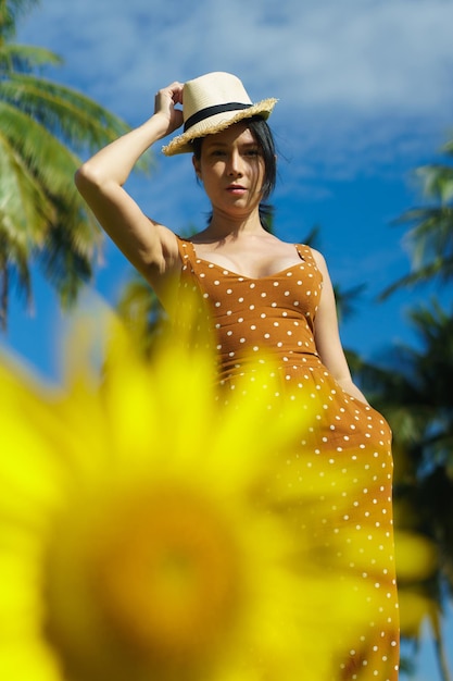 Asian Woman 40s LGBT transgender express feeling Happy Smile fun under sunshine in Sunflower yellow flower field over blue sky mountain Female poses for fashion shooting in outdoors landscape