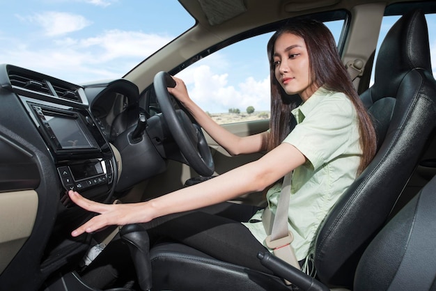 Asian woman adjusting air conditioning inside the car