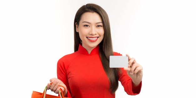 Asian woman in ao dai traditional red dress holding shopping bag and paid via credit in Lunar New Year Festival
