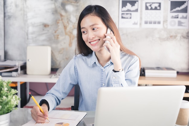 La donna asiatica sta lavorando felicemente nell'ufficio