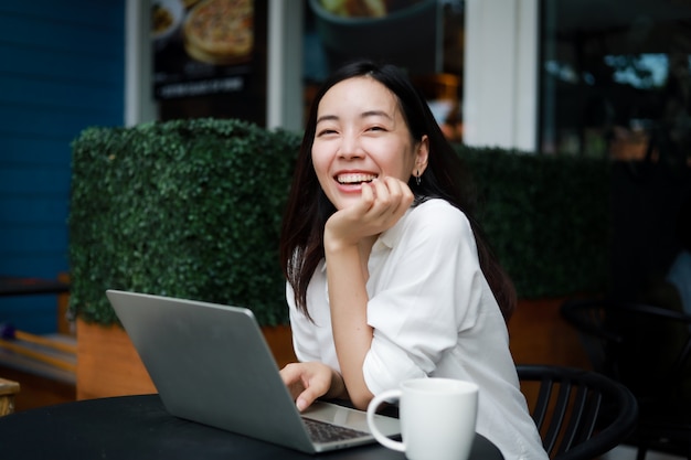 Фото Азиатская женщина в кафе работает на ноутбуке