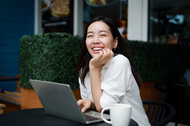 写真 ラップトップに取り組んでいるカフェでアジアの女性