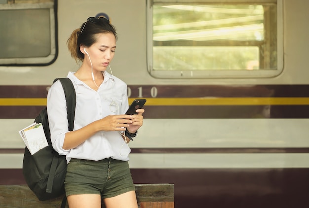 アジアの女性のバックパック旅行者。列車の駅に立つ女性