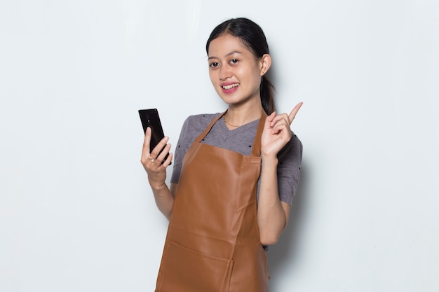 アジアの女性バリスタは携帯電話カフェサービスコンセプトでエプロンを着用