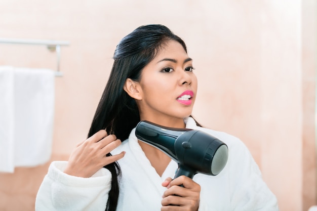 Asian woman in bathroom drying hair