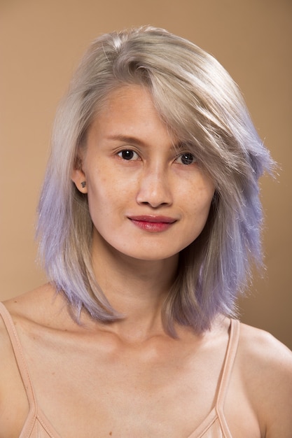 Asian Woman before applying make up silver gray hair style. no retouch, fresh face with lips, eyes, cheek, nice smooth skin. Studio lighting beige yellow background, for aesthetics therapy treatment