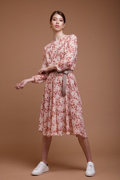 Asian woman in beige dress floral pattern posing over brown coffee background Studio Shot Portrait