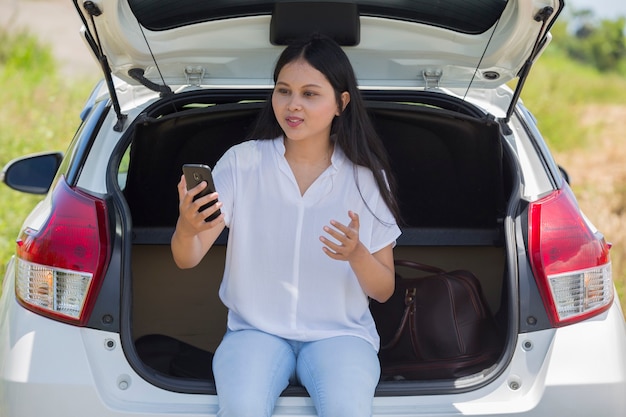 スマートフォンを使用して車の横にアジアの女性