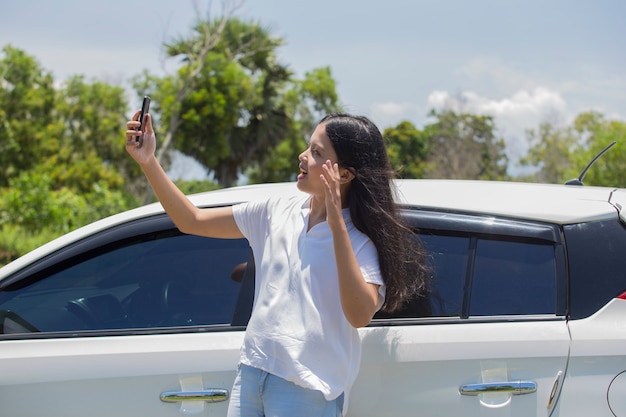 スマートフォンを使用して車の横にアジアの女性