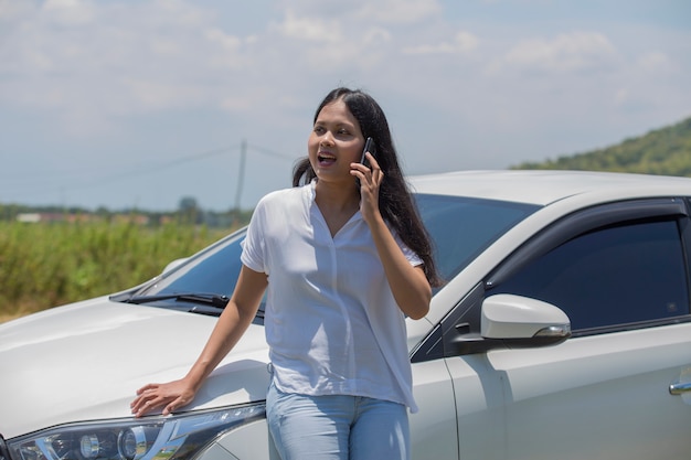 スマートフォンを使用して車の横にアジアの女性