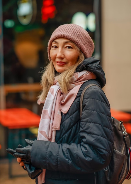 Donna asiatica con un cappotto nero e un cappello che cammina per la città d'europa invernale